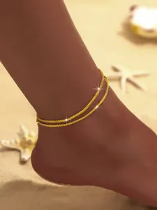 Detaillierte Nahaufnahme einer doppelten Sternenlicht-Fußkette mit Glitzer am Strand.