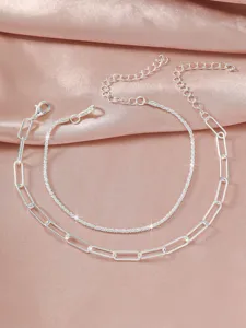 Nahaufnahme der doppelumtosten silbernen Fußkette mit funkelnden Details und Gliederkette.