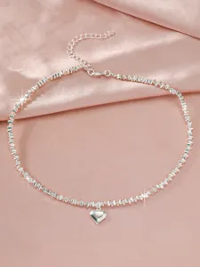 Detailed shot of a delicate silver heart pendant clavicle chain with faceted bead links.
