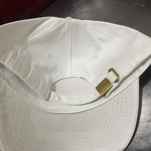 Primer plano detallado de la hebilla metálica ajustable y las costuras en la parte posterior de la gorra.