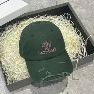 Primo piano di un cappellino da baseball verde scuro invecchiato con ricamo in confezione.