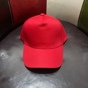 Vista detallada de gorra de béisbol roja lisa de cinco paneles con tela de algodón premium.