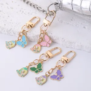Detail view of colorful butterfly metal enamel keychain, featuring cute charms and gold hardware.