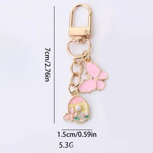 Gold tone alloy keychain featuring pink enamel butterfly and pearl round flower pendant charms.