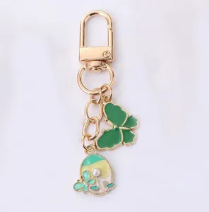 Close-up of gold alloy keychain with green enamel butterfly and colorful round pearl charm.