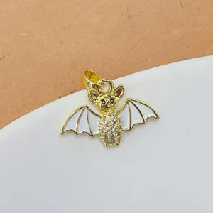 Gros plan de pendentif chauve-souris doré, avec strass étincelants et ailes émaillées blanches.