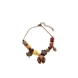 Detail shot of handmade vintage wooden bead bracelet featuring autumn leaves and natural nut charms.