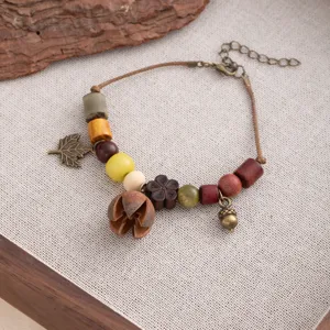 Close-up of vintage handmade wooden bead bracelet with natural acorn and leaf charms detail.