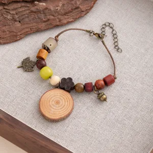 Vintage wooden bead bracelet with acorn leaf charms and tree slice pendant detail close up shot.