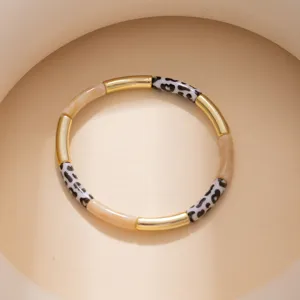Detailed close-up of geometric color-blocked bracelet featuring gold, beige, and leopard segments.