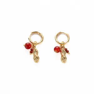 Close-up detail of exquisite gold hoop earrings featuring playful peanut pendants and red beads.