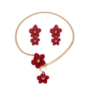 Vista dettagliata del pendente con fiore rosso e catena a serpente dorata del set di gioielli.