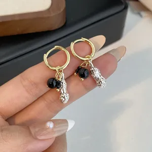 Gold hoop earrings featuring black beads and textured silver peanut pendants for chic style.