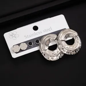 Detailaufnahme der Edelstahl Creolen Ohrringe mit texturierter runder Metalloberfläche.
