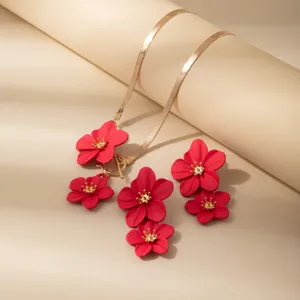 Primo piano dettagliato dei ciondoli a fiore rosso e della collana a catena di serpente.