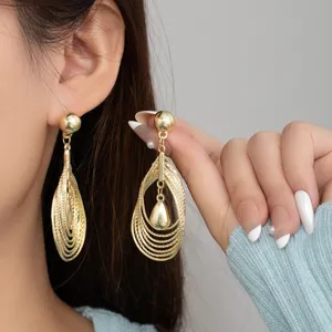 Detailed shot of gold-plated geometric hollow teardrop dangling earrings, exquisite texture.