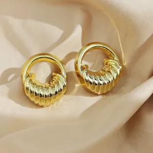 Boucles d'oreilles créoles épaisses nervurées en or, détail texture géométrique luxueuse.