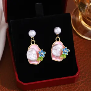 Close-up detail of baroque pearl flower enamel drop earrings with French retro Monet garden style.