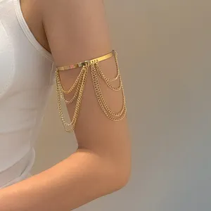 Primer plano de un brazalete de metal dorado minimalista con cadenas colgantes.