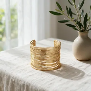 Brazalete de alambre de metal dorado multicapa, detalle de brazalete geométrico elegante.