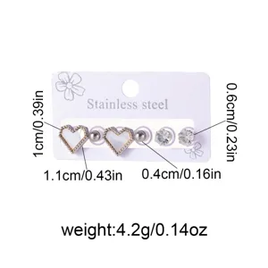 Stainless steel stud earrings set with heart and crystal design, delicate jewelry detail shot.