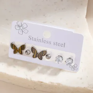 Close-up detail of stainless steel butterfly and diamond stud earrings set on display card.