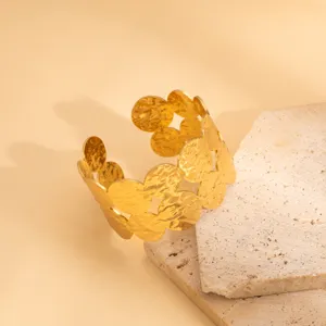 Detailed shot of a gold hammered geometric cutout open cuff bracelet on stone prop.