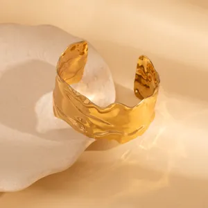 Close-up shot of the irregular gold open cuff bracelet, showcasing its unique wavy texture.