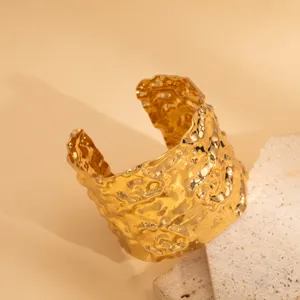Gold irregular textured wide cuff bracelet detail, open geometric metal hand jewelry design.