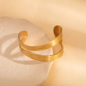 Detailed view of wide gold metal open cuff bracelet, geometric layered design, modern aesthetic.