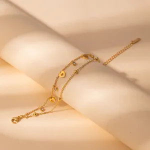 Stainless steel gold double layer bracelet detail, heart pendant and crystal charms macro shot.