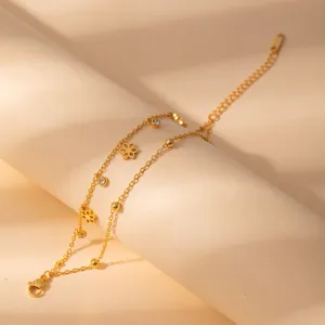 Close-up of a stylish double-layer gold stainless steel bracelet with delicate flower charms.