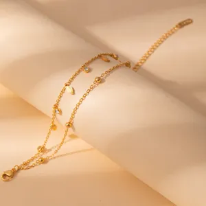Dainty double layer gold stainless steel chain bracelet with crystal and leaf charms.