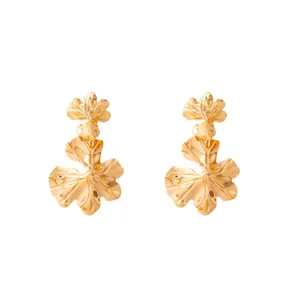 Gold metallic hollow leaf ear studs detail, elegant retro style jewelry close-up view accessory.