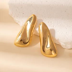 Close-up detail of geometric gold metallic teardrop earrings displayed on a textured stone prop.