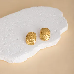 Close-up view of gold textured geometric earrings showcasing unique hammered surface detail.