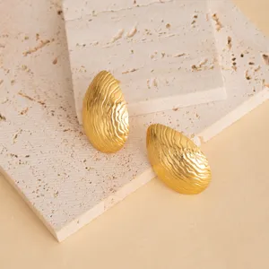 Gold stainless steel textured leaf stud earrings detail shot, minimalist geometric design.