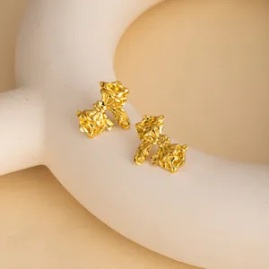 Detail view of vintage metallic flower stud earrings, unique artistic design, glowing golden finish.