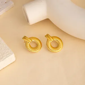 Close-up of vintage gold metal geometric textured stud earrings, minimalist modern jewelry detail.