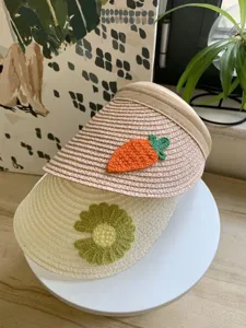 Nahaufnahme des Stroh-Sonnendachs für Kinder, handgehäkelte Karotten- und Blumendetails.