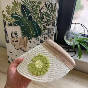 Detailaufnahme eines süßen Kinder-Strohvisors mit einer grünen Häkelblumen-Applikation.