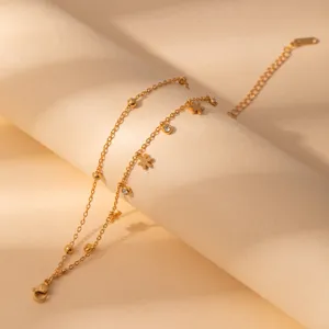 Detailed shot of gold-plated stainless steel layered bracelet with cute flower and crystal charms.