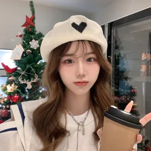 Detail view of the stylish beige knit beret with a cute black pixel heart pattern.
