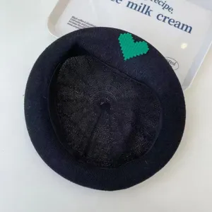 Detail shot of black knit mesh beret with green pixel heart patch, breathable summer hat.