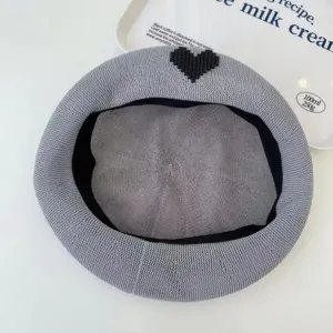 Grey knitted mesh beret detail close up, breathable summer painter hat with black heart.