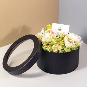 Detailed view of black round window gift box filled with artificial flowers and card.
