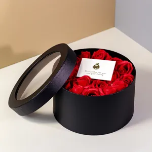 Black round gift box with clear window lid and red artificial roses, perfect for romantic surprises.