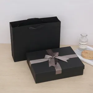 Detail view of luxury black gift box with grey ribbon bow and matching paper bag for presents.