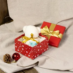 Red Christmas gift box detail showcasing cute white plush bear, gold bow and festive decor.