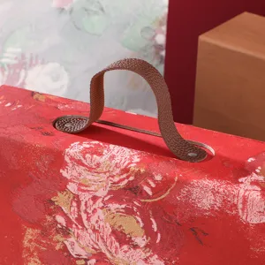 Detail shot of festive red gift box handle, elegant floral pattern, premium packaging.